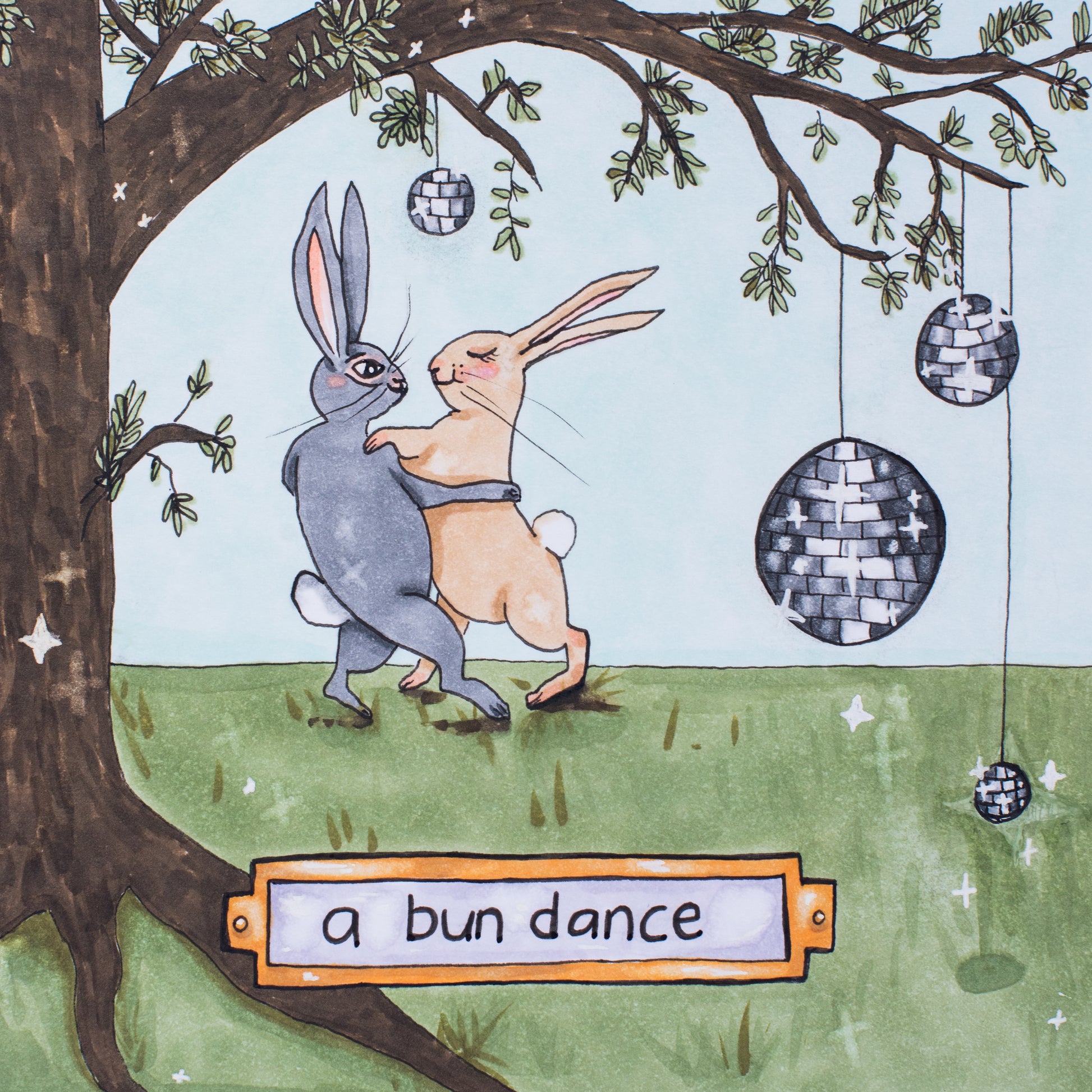 A square illustration drawn in Copic markers. Two rabbits dance in a ballroom style embrace, underneath a tree hung with disco balls. On the bottom is a plaque that reads "a bun dance". 